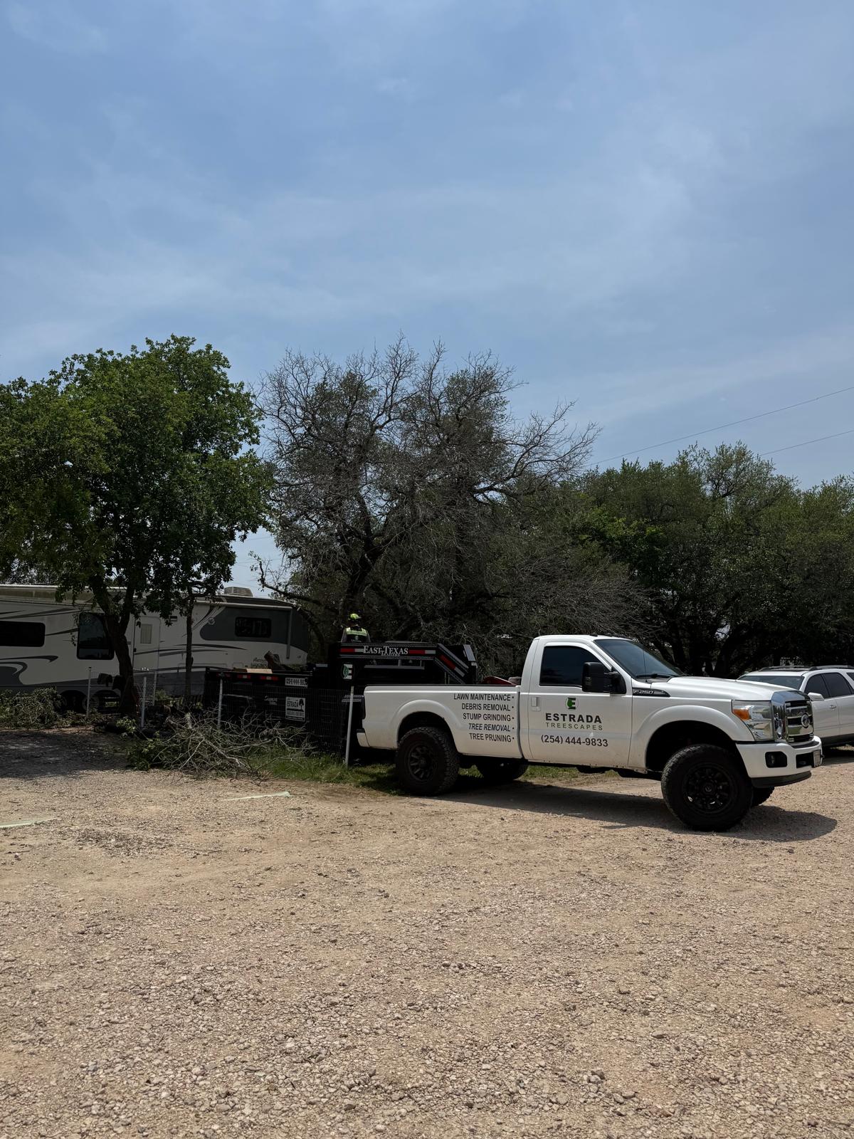 Estrada Treescapes Ford F-250 service truck and chipper trailer at a tree removal job site